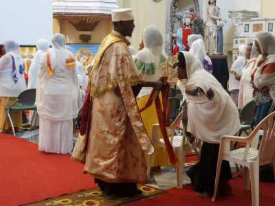 Il sacerdote dopo aver cantato alcuni brani nella lingua gemitica ge'ez e recitato i versi di alcuni salmi, prende una croce in metallo e passa tra le sedie facendola baciare ai presenti